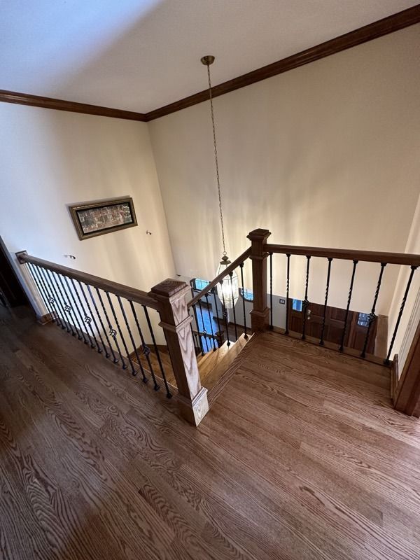 Stair landing with wooden banister, dark wood floor, cream walls, and a hanging light fixture
