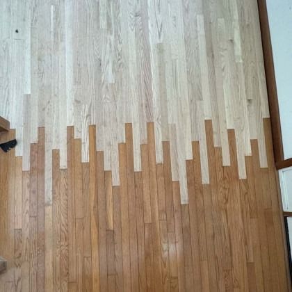 Light and dark wood flooring meeting in a jagged transition line