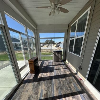 Covered porch with ceiling fan, sliding glass doors, and a small cabinet overlooking a yard and street