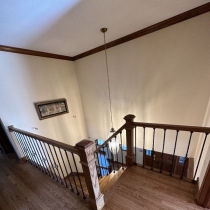 Stair landing with dark wood railings and cream walls, viewed from an upstairs hallway