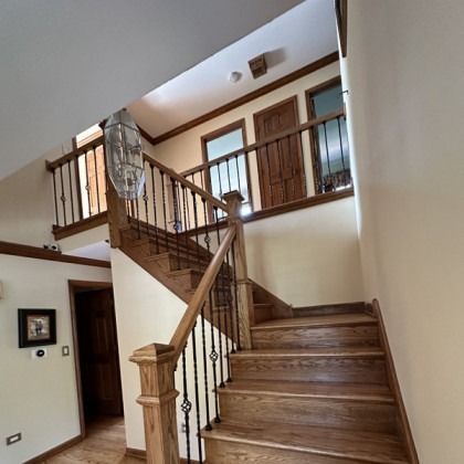 Interior staircase with wooden banister and tiled steps in a beige entryway