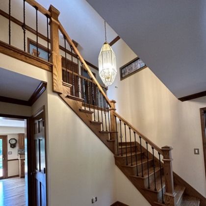 Wooden staircase in a foyer with beige walls and a hanging pendant light