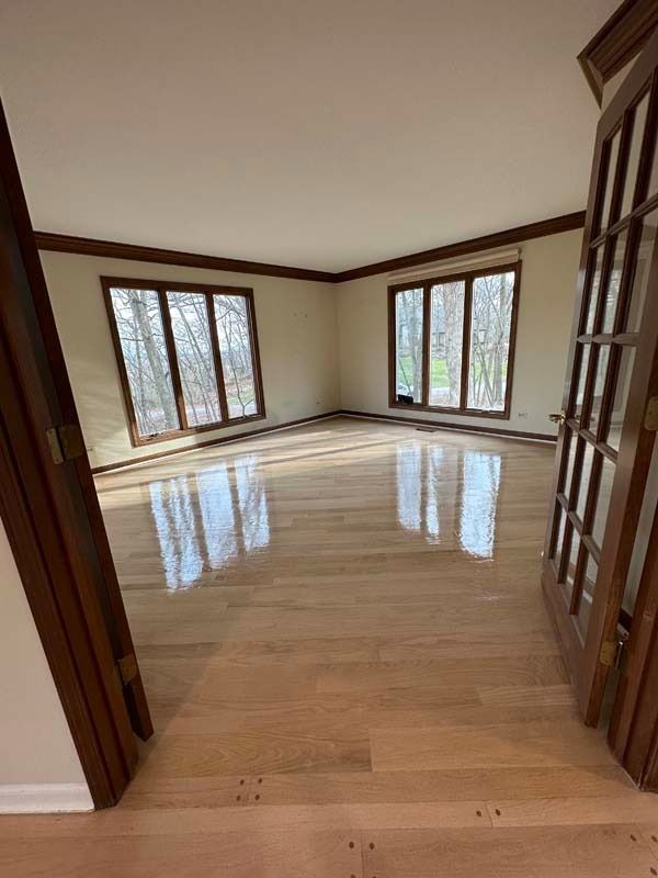 Empty bright living room with polished wood floor and large windows on three walls