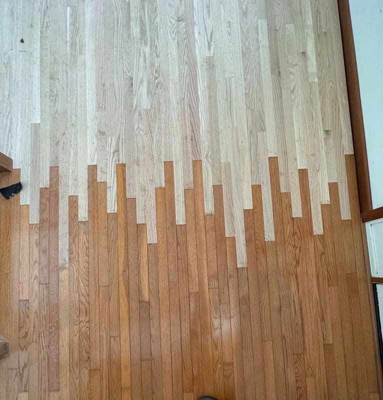 Wooden floor with a jagged transition from light to dark planks running across the middle