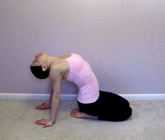 A woman in a pink tank top is doing a yoga pose