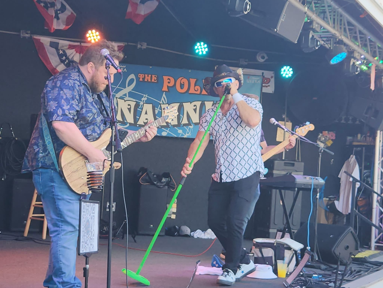 Two men perform on stage with a pumpkin backdrop. One sings, the other plays a bass guitar.