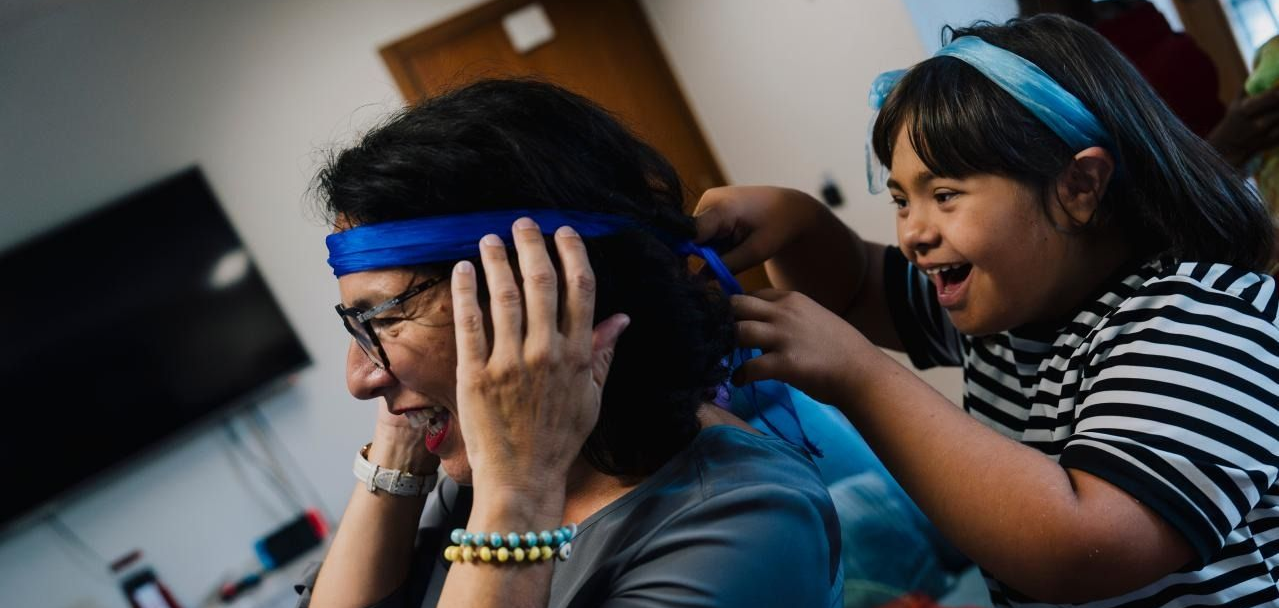 Person getting a blue headband adjusted by another person in a room