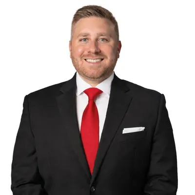Man in black suit with red tie and white pocket square on a white background