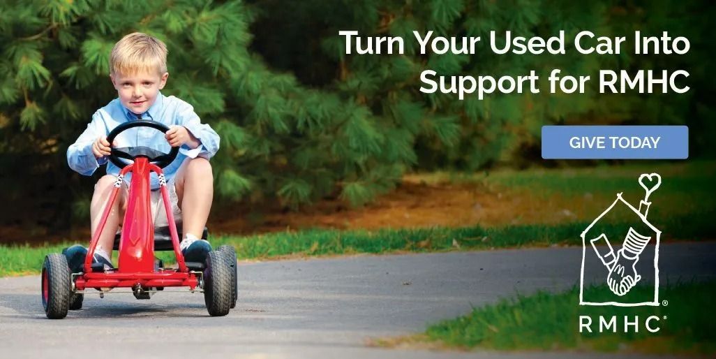 Child riding a red tricycle on a road beside text: “Turn Your Used Car Into Support for RMHC”