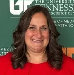 Smiling woman in a red top before a University of Tennessee Chattanooga backdrop