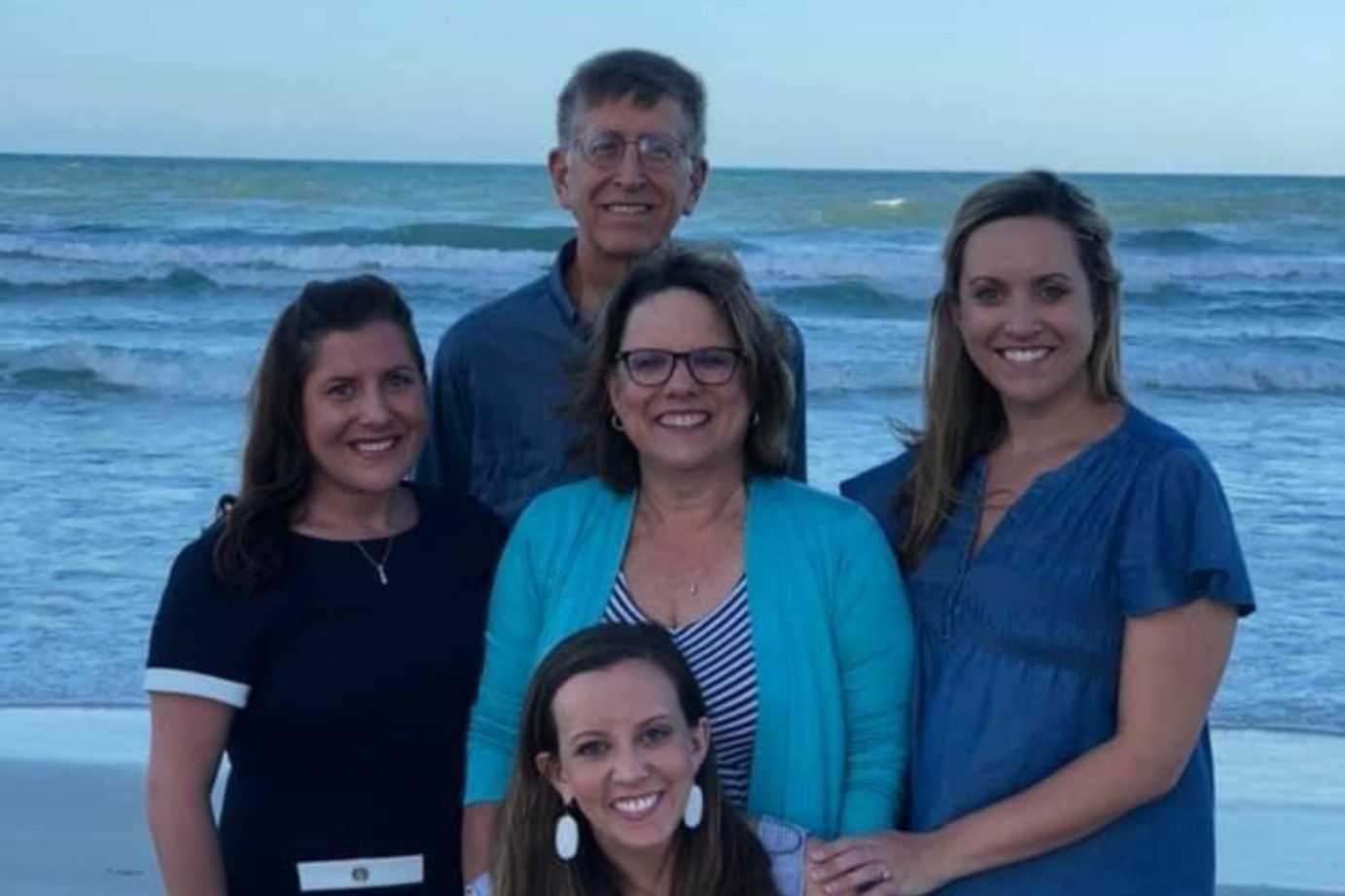Sallie Brooks with her family on the beach, smiling together at sunset.