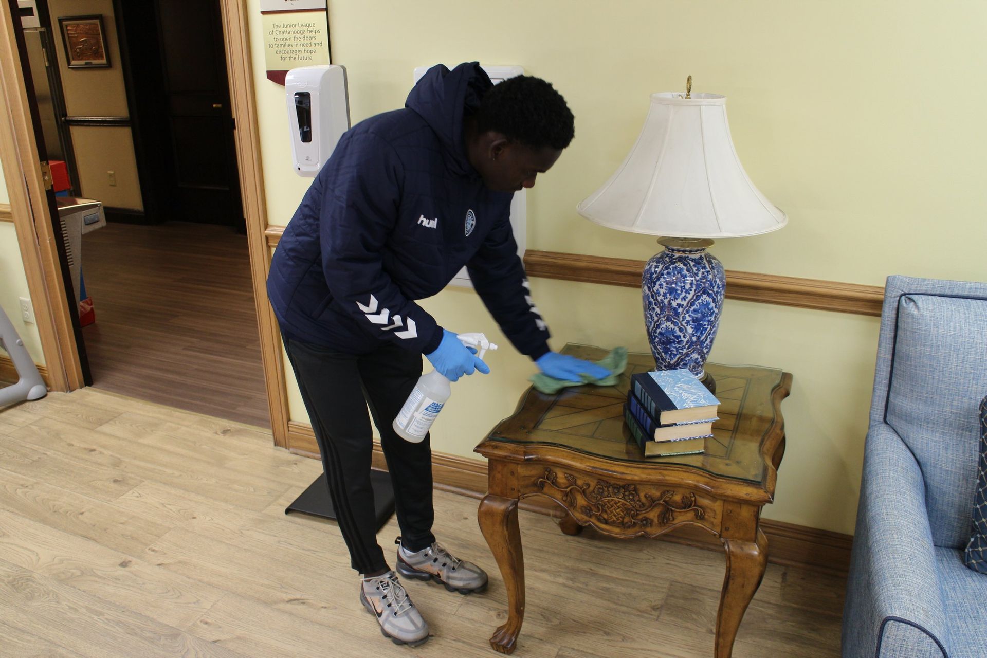 A volunteer wipes down and disinfects furniture in a family guest room.