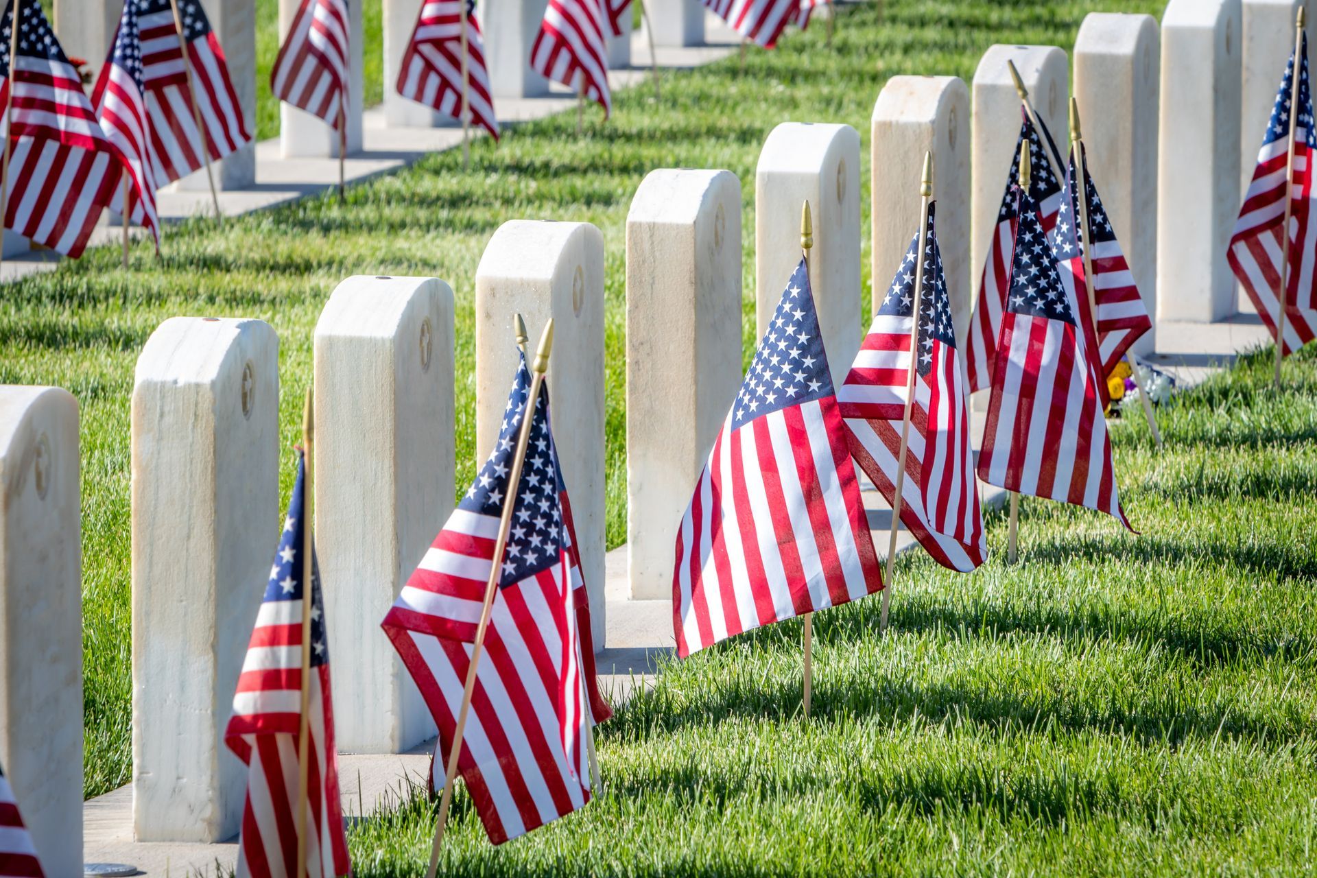 a row of graves with american flags in front of them