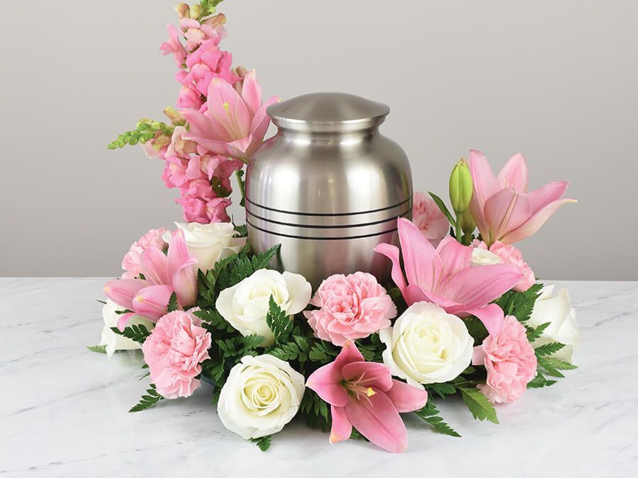 a silver urn surrounded by pink and white flowers