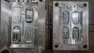 Two halves of a metal mold, each with four cavities for shaping objects, likely plastic parts.