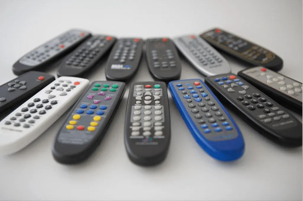 A collection of various TV remote controls arranged on a white surface.