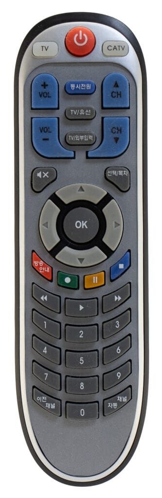 Gray remote control with several buttons. Has number keys, navigation buttons, and a power button.