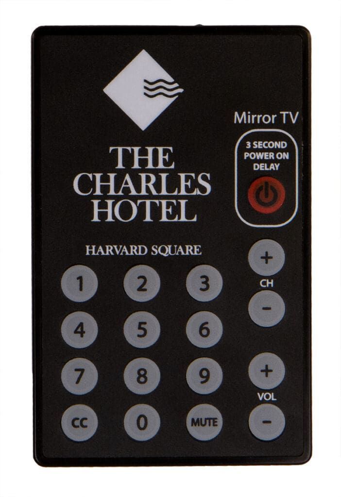 Black remote control with "The Charles Hotel" logo and channel/volume buttons.