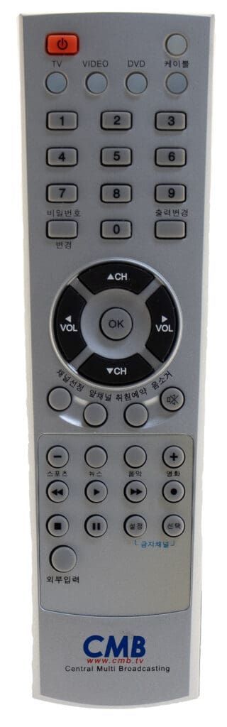 Silver remote control with various buttons, including number keys and navigation controls. The brand name