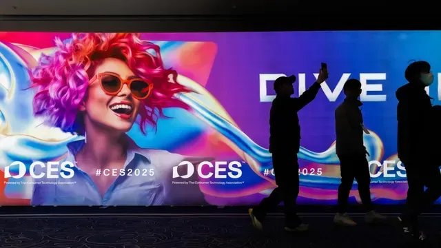 People walk past a CES 2025 promotional display. The display features a colorful graphic of a woman wearing sunglasses.