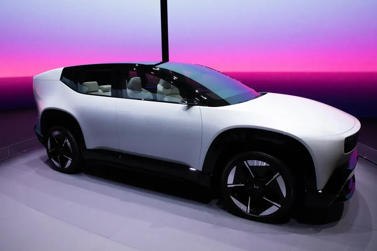 White concept car on display with black wheels, set against a pink and purple backdrop.