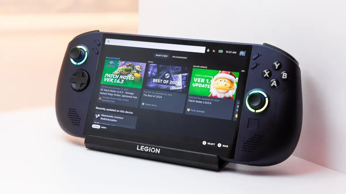 Dark-colored handheld gaming device, with screen displaying a game store. Leaning on a stand.