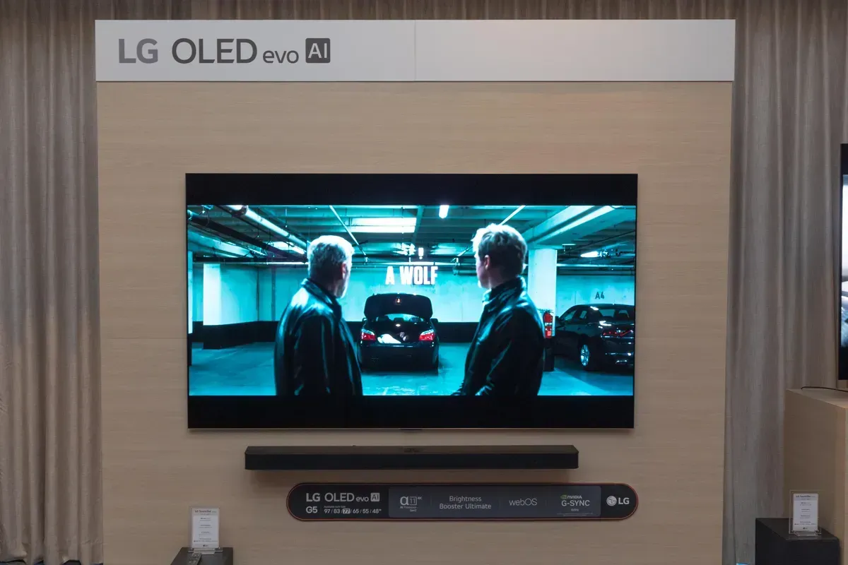 LG OLED evo AI TV displaying a scene from a movie, mounted on a wall with a sound bar.