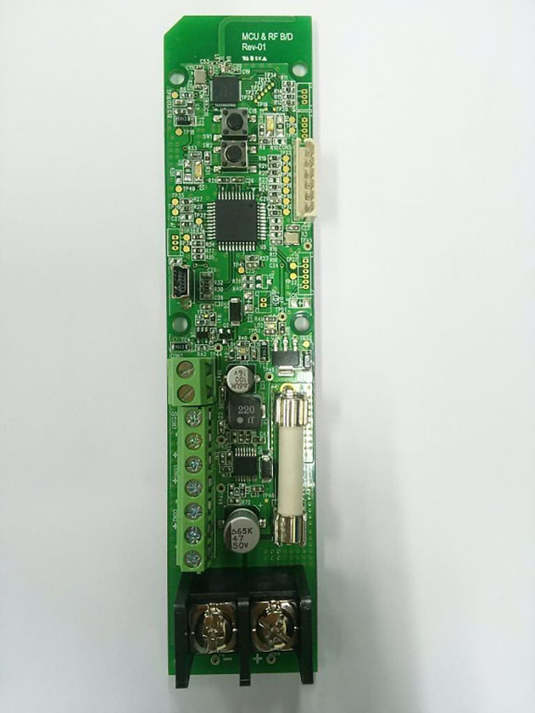 Green circuit board with various electronic components, including connectors, chips, and a fuse.