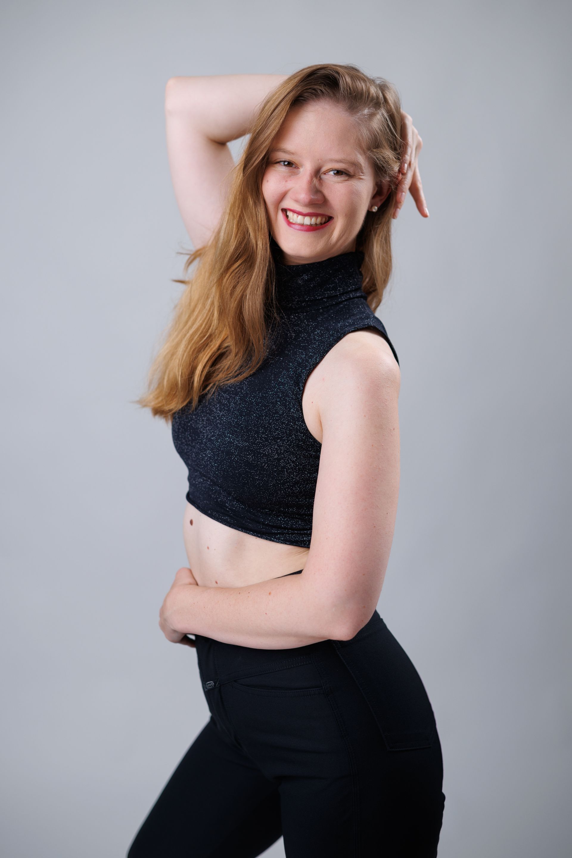 A woman in a black crop top is posing for a picture.