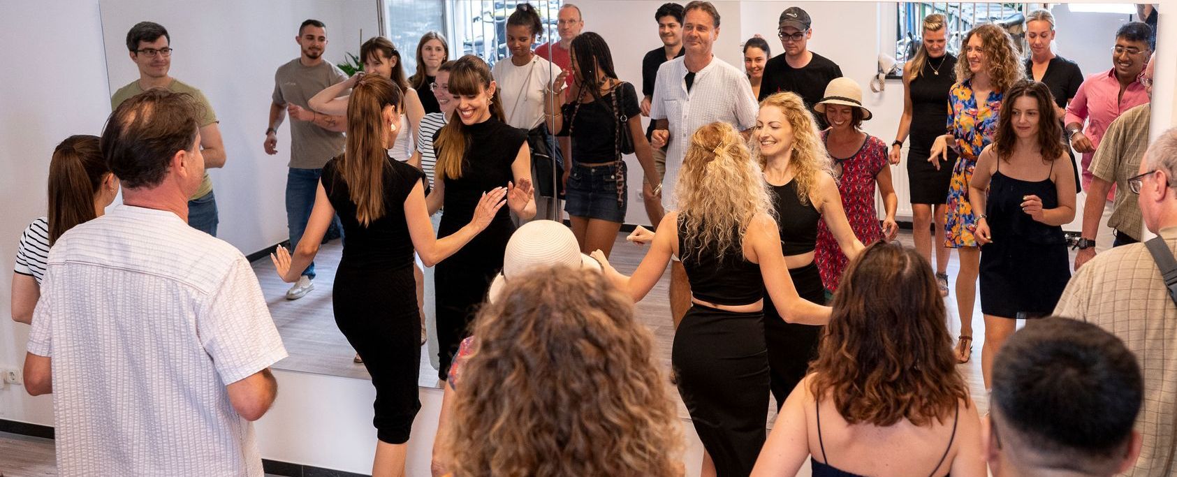 A group of people are dancing in a circle in a room.