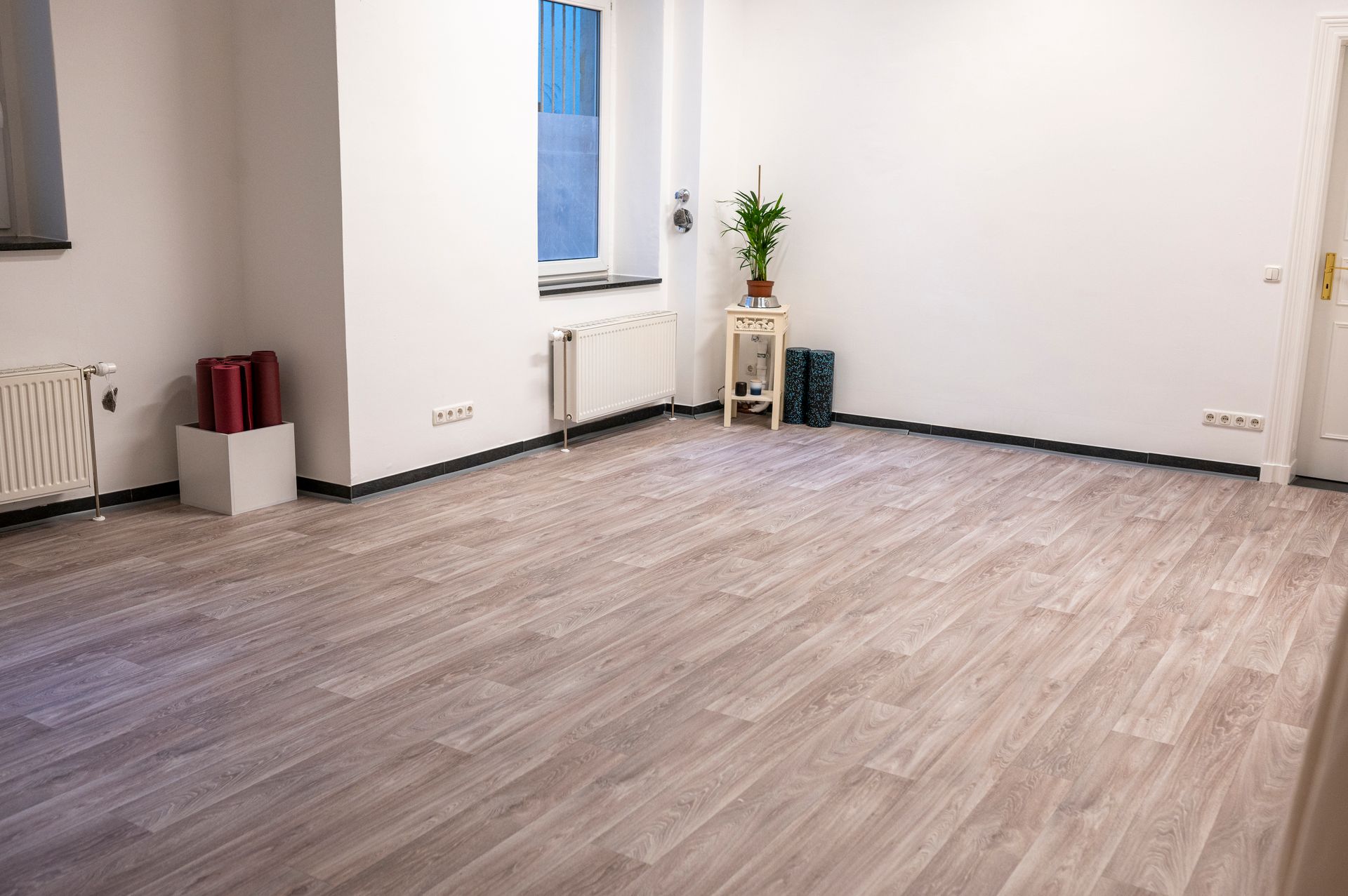 An empty room with a wooden floor and white walls.