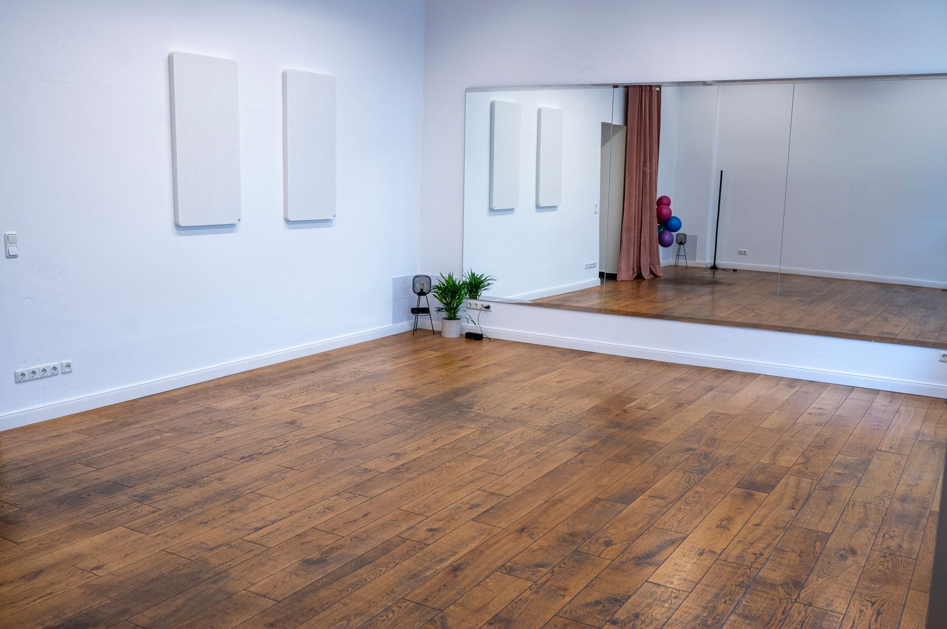 An empty room with wooden floors and a large mirror
