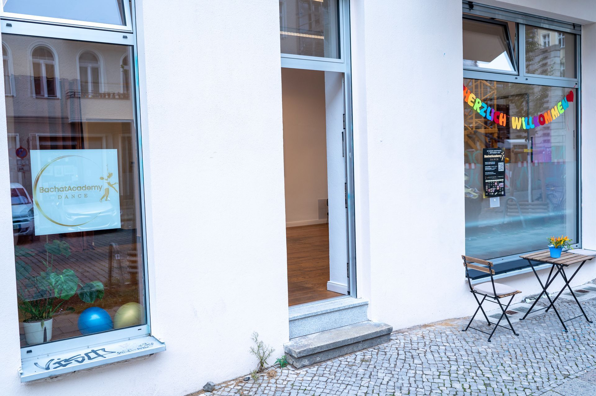 A white building with a table and chairs in front of it