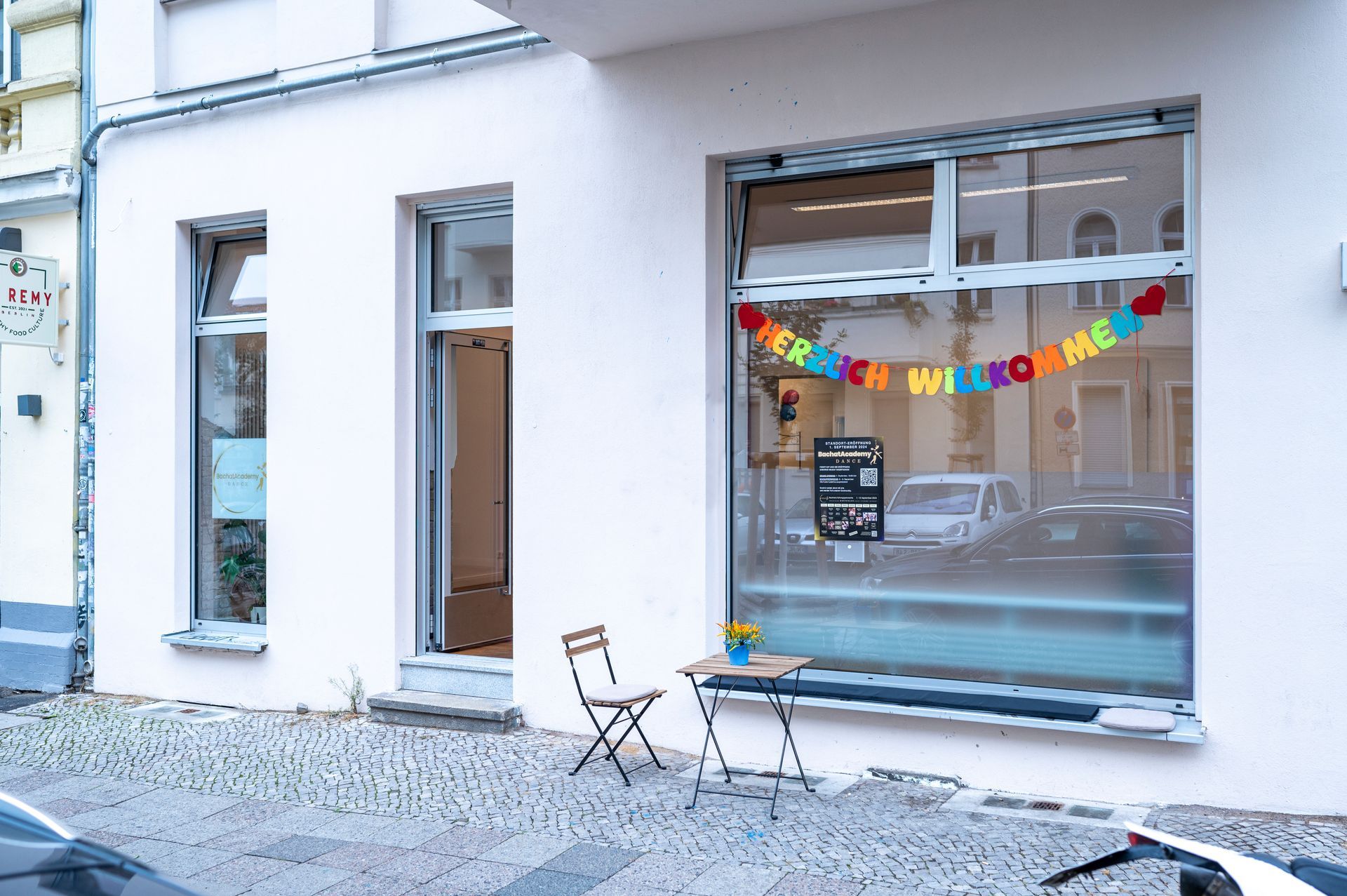 A white building with a table and chairs in front of it.