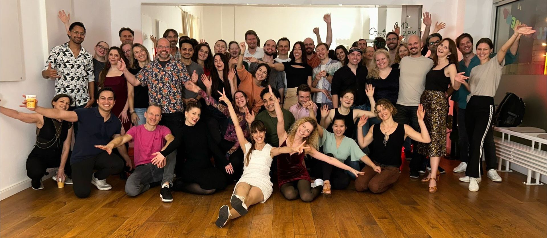 A large group of people are posing for a picture in a dance studio.
