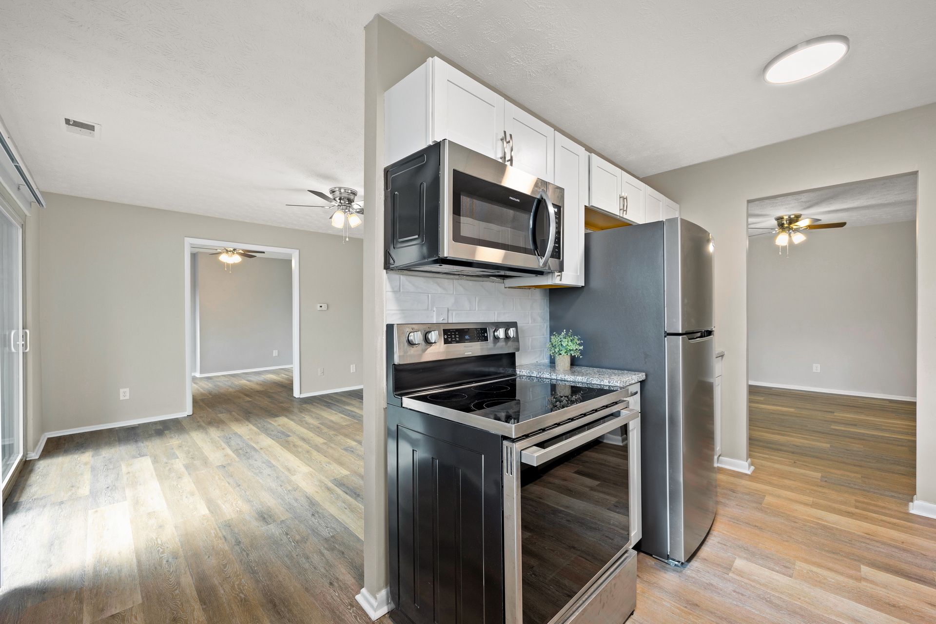 Apartment kitchen with stainless steel appliances opening into living and dining area.