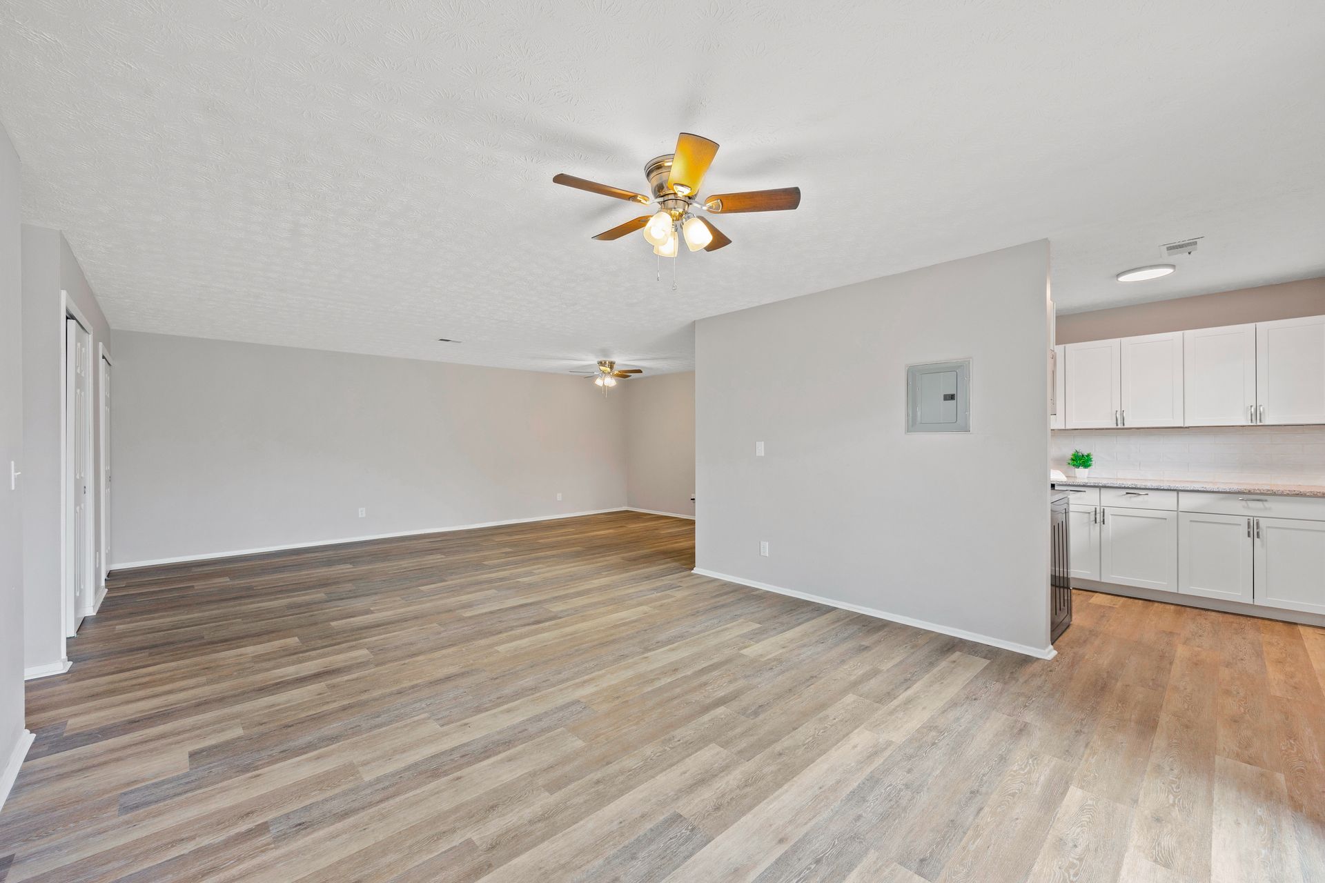 Large apartment living room with wood-style flooring, ceiling fan, and open floor plan.