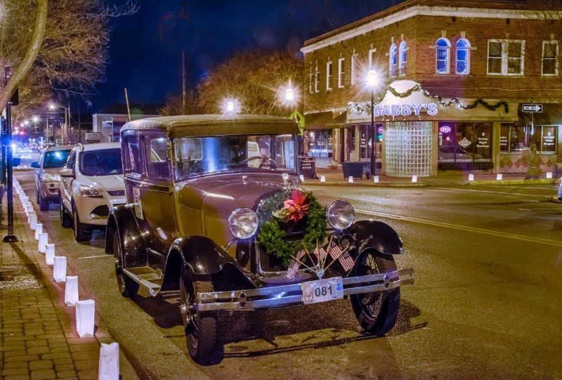 Historic Wyoming, Ohio street view at night with vintage car, shops, and glowing streetlights.