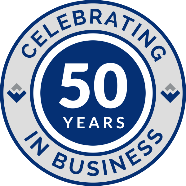 A circular logo with the text "CELEBRATING 50 YEARS IN BUSINESS" in navy blue on a gray background, featuring a blue center.