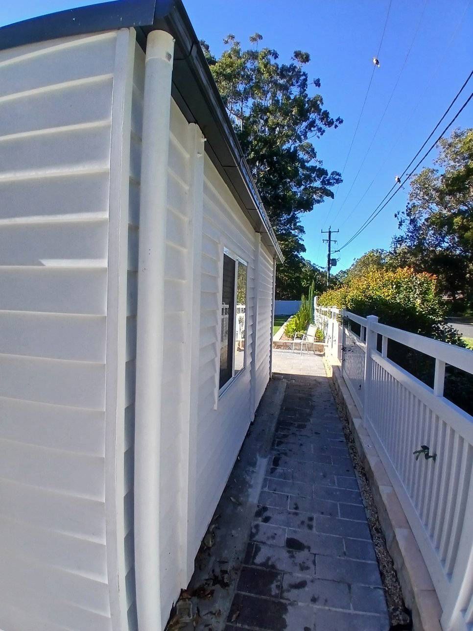 A Narrow Stone Pathway Between a White House Exterior — APD Plumbing In Beechwood, NSW