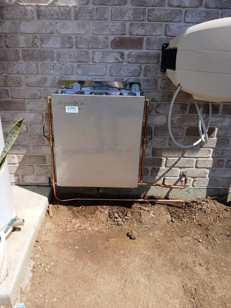 A Rectangular Metal Pool Heater Mounted on a Brick Exterior Wall — APD Plumbing In Coffs Harbour, NSW