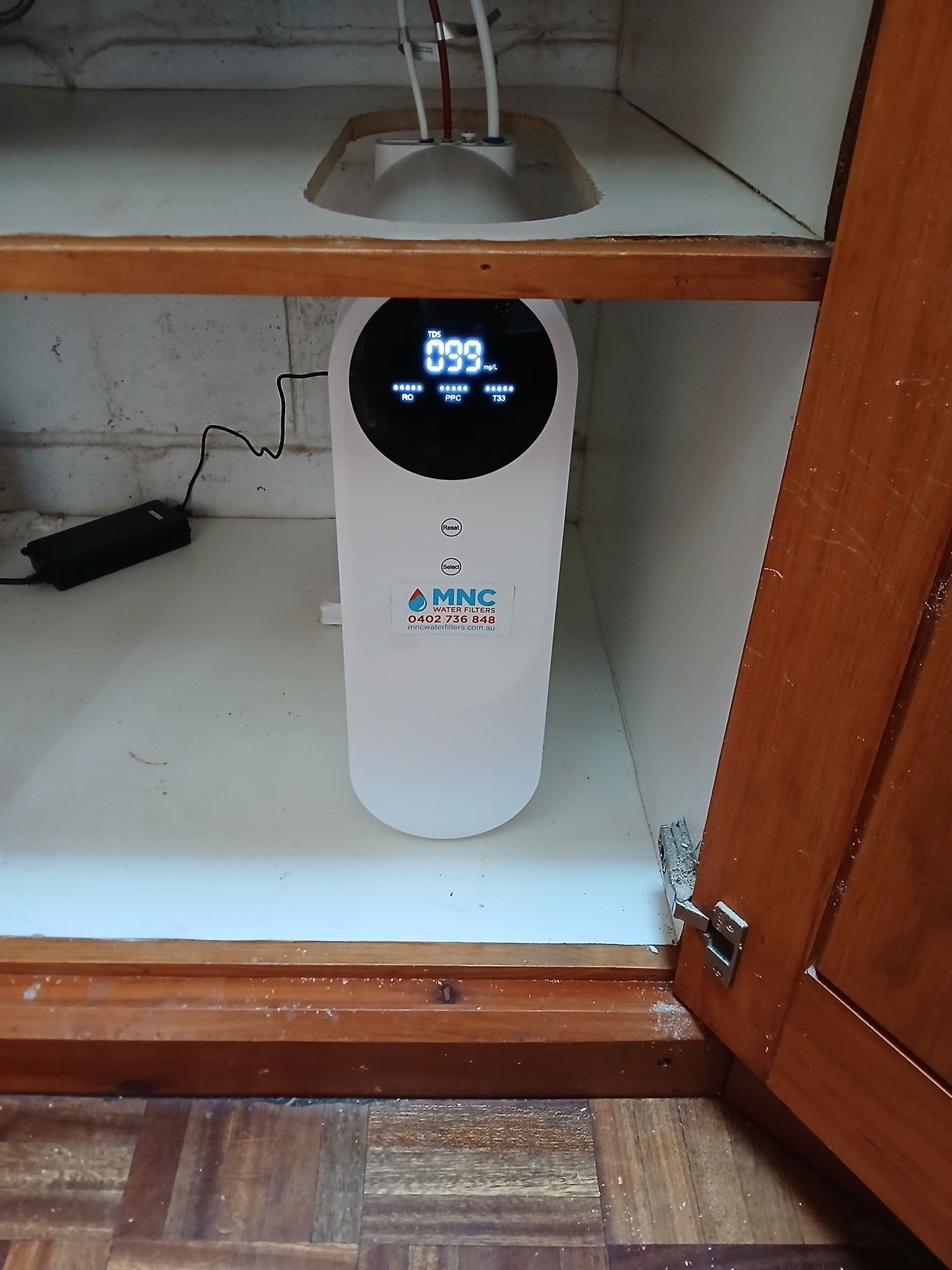 Water Purifier Under A Kitchen Sink Cabinet, With A Lit Display — APD Plumbing In Beechwood, NSW