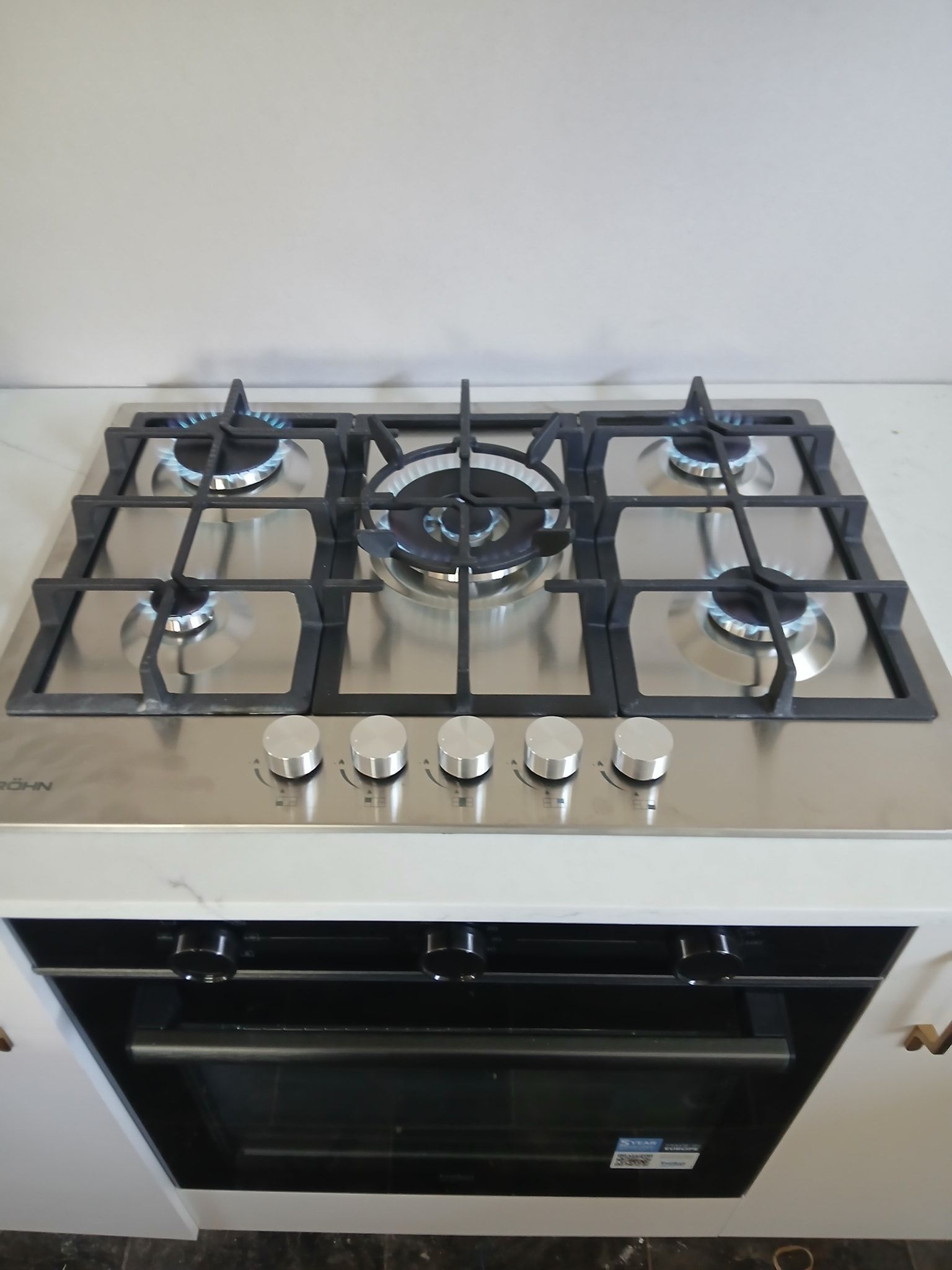 Stainless Steel Gas Cooktop With Five Burners and Black Iron Grates — APD Plumbing In Beechwood, NSW