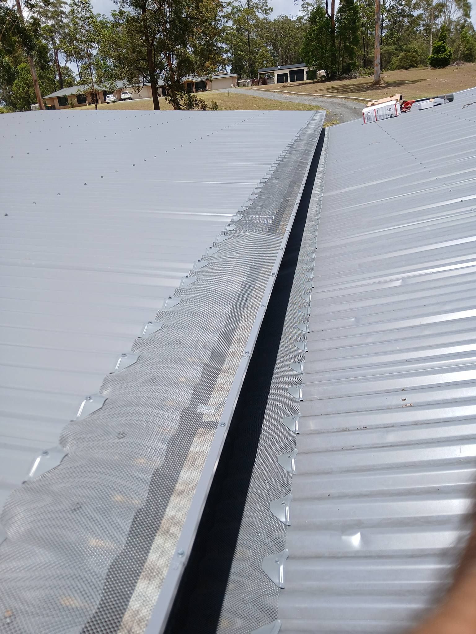 A Metal Roof Valley Gutter Covered With a Protective Mesh Guard — APD Plumbing In Beechwood, NSW
