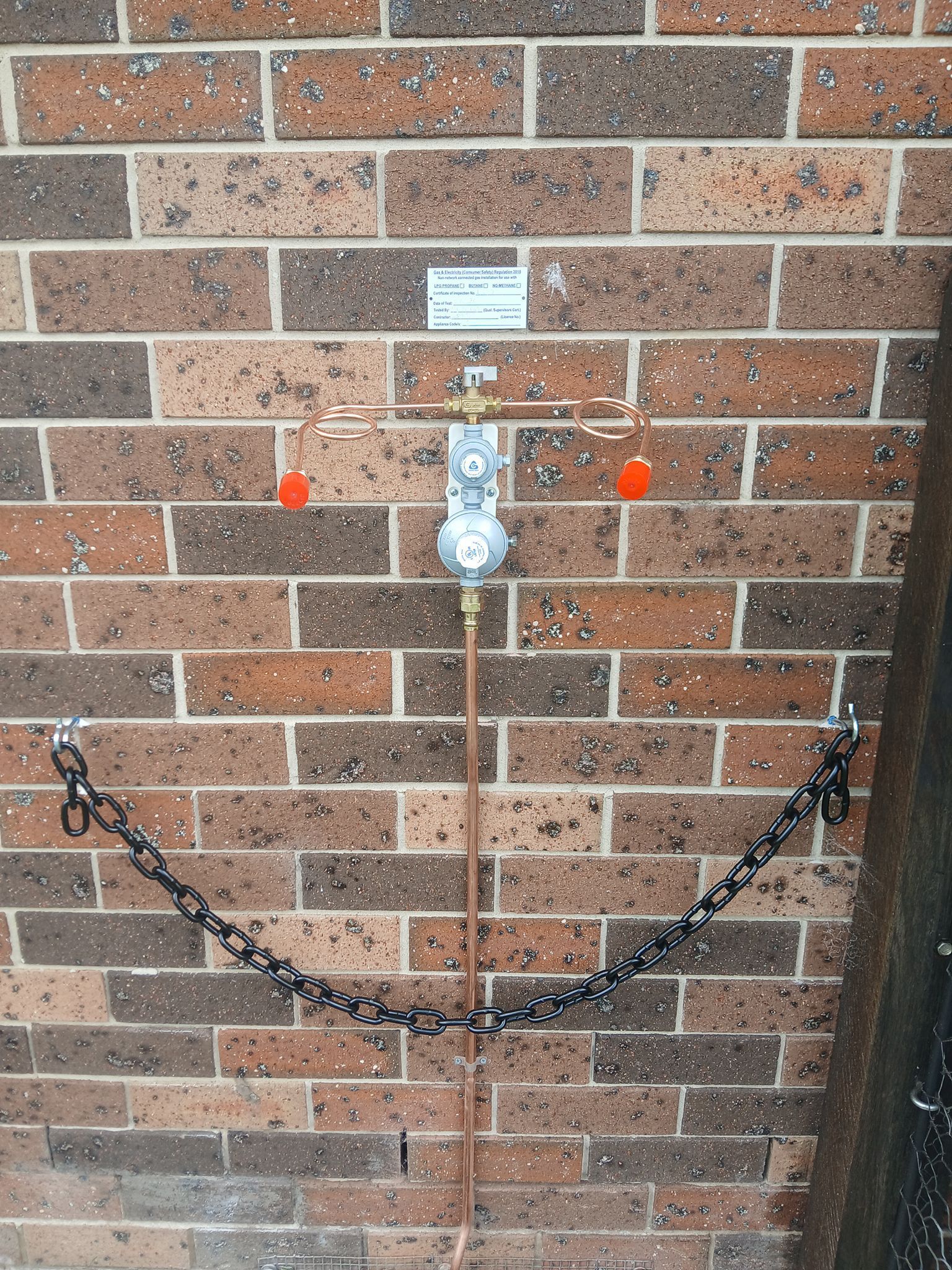 A Gas Meter Regulator Assembly Mounted on a Brick Wall — APD Plumbing In Beechwood, NSW