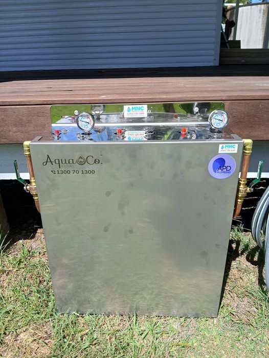 Stainless steel appliance cabinet outdoors on grass in front of a wooden deck and siding.