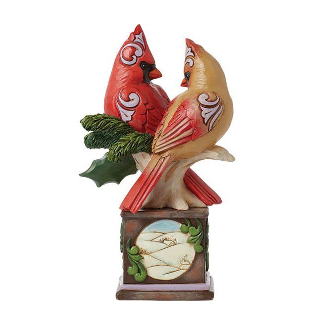 Twee kardinaalvogelbeeldjes zitten op een tak, bovenop een kleine decoratieve sokkel.