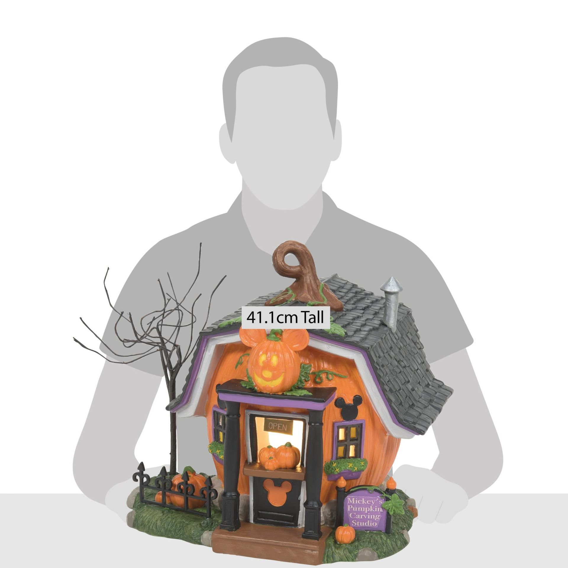 Een Halloweenwinkel in de vorm van een pompoen met een uitgehouwen gezicht, een zwart dak en herfstdecoratie.