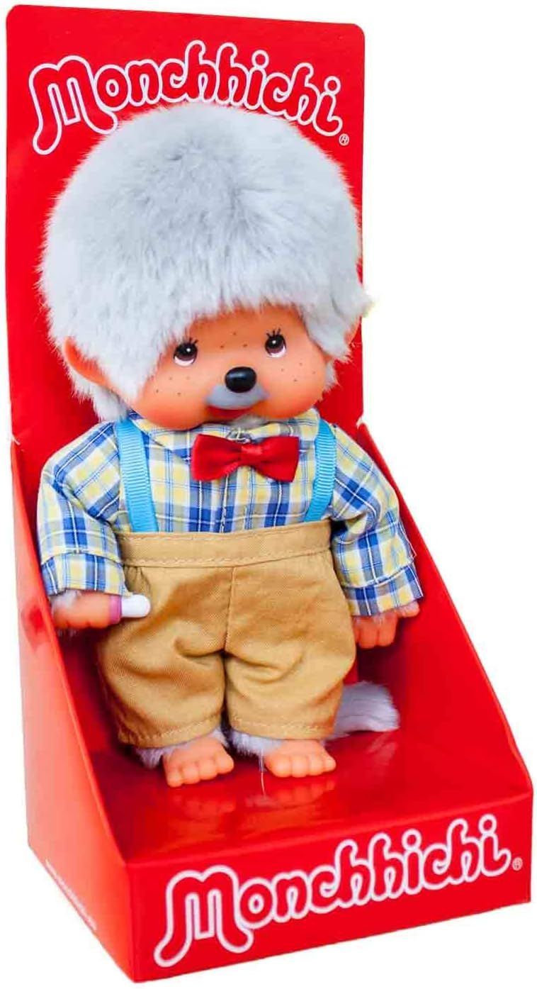 Een pluche Monchhichi in een rode doos, gekleed in een geruit overhemd, vlinderdas en bretels.