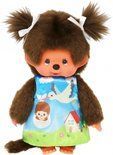 Monchhichi-pop met bruine vacht, gekleed in een blauwe jurk met een huis- en vogelmotief.